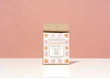 A kraft paper bag of Harbor Herbalist Digest Loose Leaf Tea stands upright on a white surface against a solid pink background. The packaging features a white label decorated with orange and pink botanical illustrations.