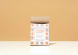 A kraft paper bag of Harbor Herbalist Think Loose Leaf Tea stands upright on a white surface against a warm beige background. The packaging features a white front label with orange and brown botanical illustrations.